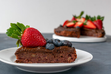Vegan date cake without sugar. Cream of avocado with cocoa. Garnished with strawberries and blueberries. Proper nutrition concept.