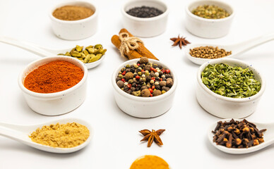 Seasonings of different varieties, on a white background, cinnamon, anise. Focus on the pepper mixture.