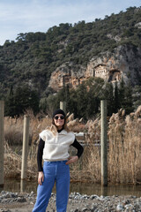 A blonde girl in front of the Rock-cut temple tombs in Kaunos Dalyan - Turkey. Ancient city of Kaunos.