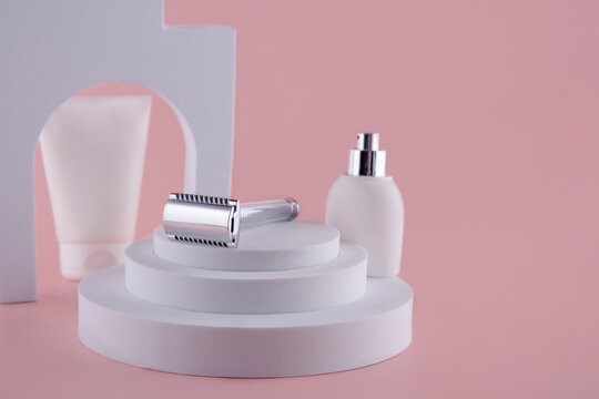 Razor and cream for sheving on white props on pink background. Space for text.