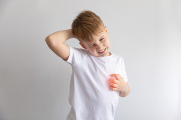 Child boy in white t-shirt isolated on white background scratching his body. Scabies, skin disease rash.