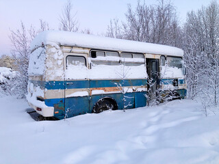 An old rusty bus stands snow-covered in a snowdrift. Apocalypse concept.