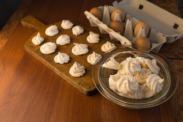 Delicious crispy homemade egg meringue, prepared with love on a wooden background, crunchy dessert for coffee or tea.