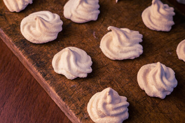 Delicious crispy homemade egg meringue, prepared with love on a wooden background, crunchy dessert for coffee or tea.