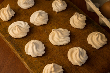Delicious crispy homemade egg meringue, prepared with love on a wooden background, crunchy dessert for coffee or tea.