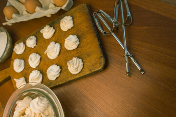 Delicious crispy homemade egg meringue, prepared with love on a wooden background, crunchy dessert for coffee or tea.