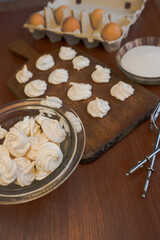 Delicious crispy homemade egg meringue, prepared with love on a wooden background, crunchy dessert for coffee or tea.