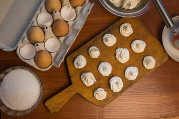 Delicious crispy homemade egg meringue, prepared with love on a wooden background, crunchy dessert for coffee or tea.