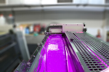 selective focus: ink carrier rollers of printing house. Light pink (purple) dyed printing ink...