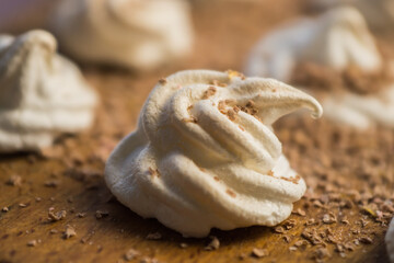 Delicious crispy homemade egg meringue sprinkled with grated dark chocolate, prepared with love on a wooden background, crunchy dessert for coffee or tea.
