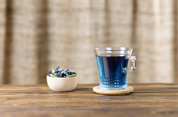 Dried flowers and a cup of pea, blue Anchan tea on a wooden table in a rustic style. Selective focus.