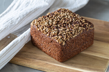 Wholemeal rye bread with sunflower seeds on cutting board.