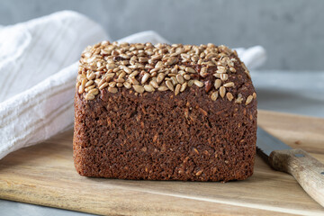 Wholemeal rye bread with sunflower seeds on cutting board.