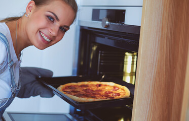 Happy young woman cooking pizza at home