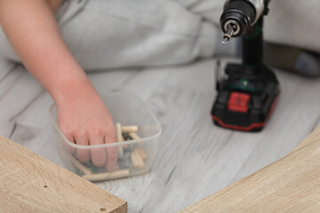 Selects the correct screw from the box to assemble the furniture.