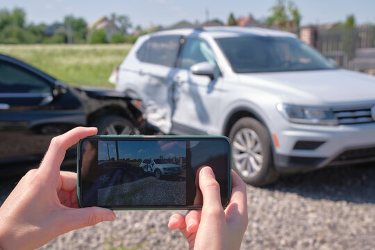 Stressed driver taking picture on sellphone camera of smashed ve