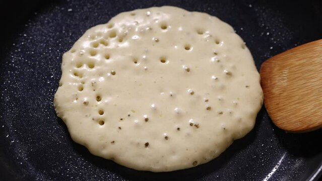 Pancake flip with wooden spatula. Cooking American traditional breakfast, close up
