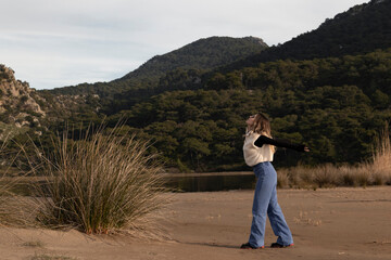 Young female stretching funny way at seaside on sandy beach.