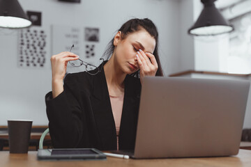 Young woman feel eye fatigue during working on laptop. Take off glasses and massage eyes