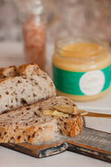 Ghee butter in glass jar and sliced bread on table. Healthy eating, breakfast