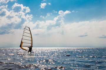 Man on a water sailing windsurfing board. - obrazy, fototapety, plakaty