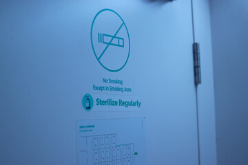 No Smoking Sign (Dilarang merokok) with Sterilize Regularly text and evacuation route text on a capsule hotel pod in Bandung