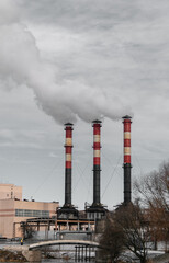 Fototapeta na wymiar Three factory chimneys release clouds of smoke into the sky. The concept of air pollution, environment, industry and ecology, global warming.