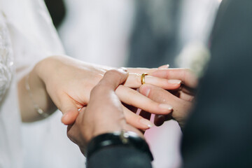 Groom puts a wedding gold ring in church during the wedding ceremony. Closeup of bride and groom hands in church