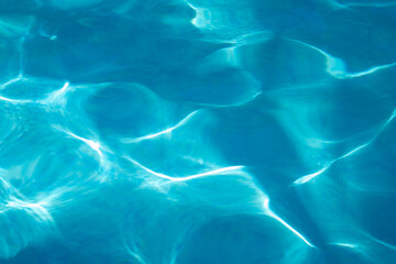 Sun glare in bright blue water. Patterns on the water from sunlight. Beautiful water texture. Sea water on a sunny day.