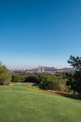 Fototapeta premium Golf course landscape with short green grass, some hills and trees. 