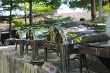 a group of Empty buffets with blurred background is being set up for an outdoor wedding concept. Catering and Garden party wedding concept background