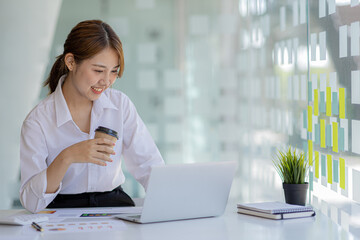 Beautiful Asian young woman looking at information on a laptop, concept image of Asian business woman working smart, modern female executive, startup business woman, business leader woman.