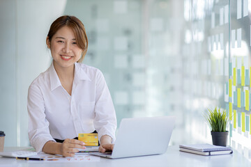 Beautiful woman holding a credit card, she uses a credit card to pay for goods and services online, the concept of using a credit card for online shopping, ordering goods and services on the website.