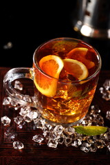 Black tea with ice cubes and mint on a black background