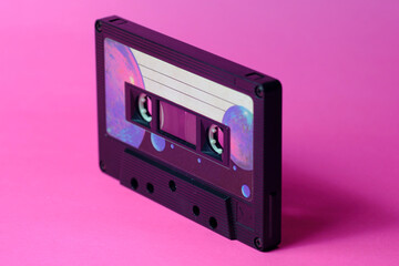 Vintage audio cassette isolated in perspective. Pink background. Warm light