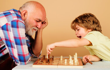 Happy kid playing chess with grandpa. Family relationship with grandfather and grandson. Board game.