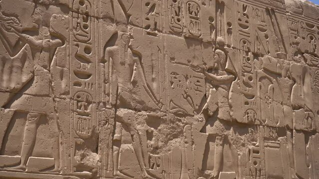 Close shot of Egyptian hieroglyphs on the wall in Hatshepsut temple. Antique stone wall with carved ancient Egyptian hieroglyphs. Shallow DOF