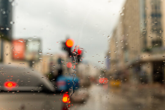 Drops accumulating on the car window in a rainy weather and the exterior view from the glass