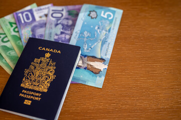 View of Canadian passport with Canadian money on brown background.