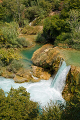 An azure waterfall surrounded by emerald greenery, taken on a summer day in Croatia