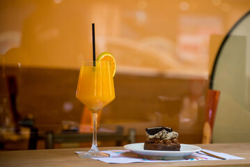 glass with orange juice on wooden table, chocolate dessert and spoon