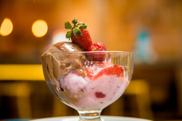 glass of ice cream with strawberries on a plate on a wooden table