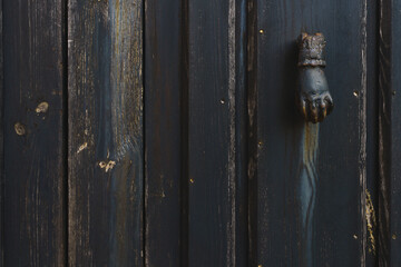 Old knocker in the shape of a hand in an old gate in the town of Llanes, Asturias, Spain 