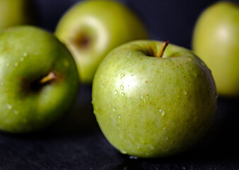 Green apple, fresh and wet fruit isolated on black background gloomy chiaroscuro mysterious atmosphere