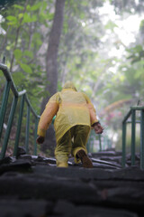An Asian girl with a yellow raincoat is climbing old stone stairs to Mount Padang Megalithic site Cianjur, West Java, Indonesia