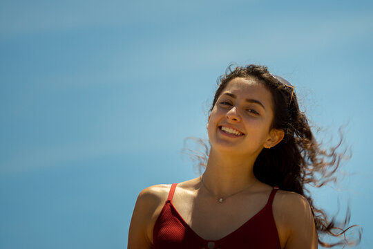 Young woman smiling under a clear blue sky