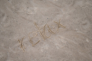 The inscription relax on the yellow sand. Holiday concept at sea.