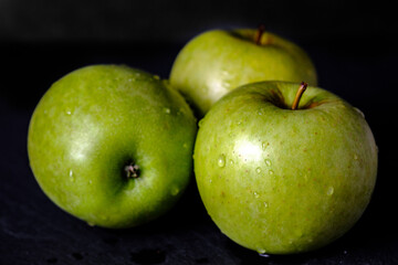 Green apple, fresh and wet fruit isolated on black background gloomy chiaroscuro mysterious atmosphere