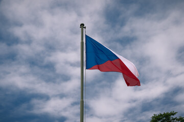 Czech Republic flag on a pole with cloudy sky in the backround