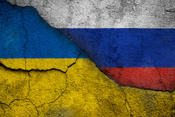 Full frame photo of weathered flags of Ukraine and Russia painted on a cracked wall. Ukraine-Russia crisis, conflict and invasion concept.
